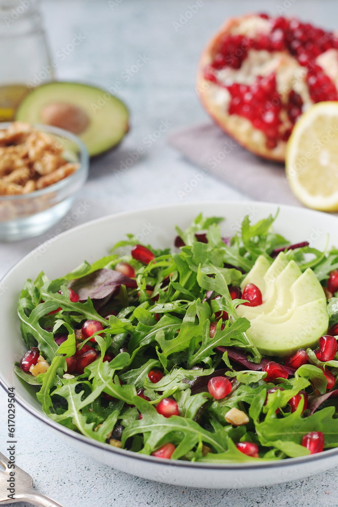 A plate with green rocket salad with pomegranate	 and avocado