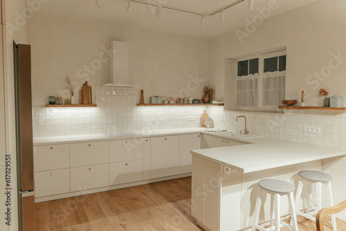 Modern kitchen interior. Stylish white kitchen cabinets with brass knobs, granite island, appliances and light in new scandinavian house. Modern minimal kitchen design