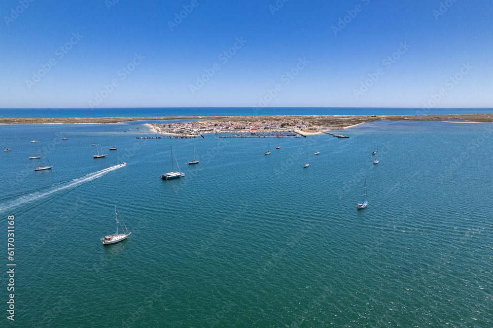 Aerial seascape view of Culatra island fishing port and beach, one of the barrier islands that protect the Ria Formosa natural park, in Algarve Tourism Destination Region, in Portugal south coast.