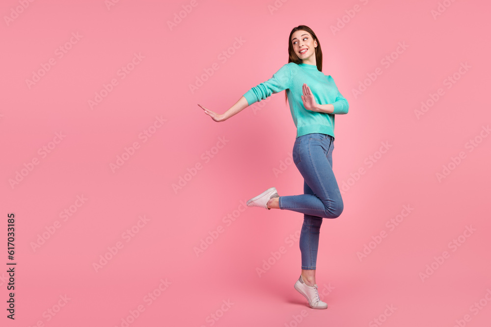Having Fun. Portrait of happy young woman dancing looking aside free space being good mood isolated over pink background