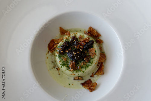 Delicious italian dessert called panna cotta aromatized with pesto sauce garnished with caramel and taggiasca olives