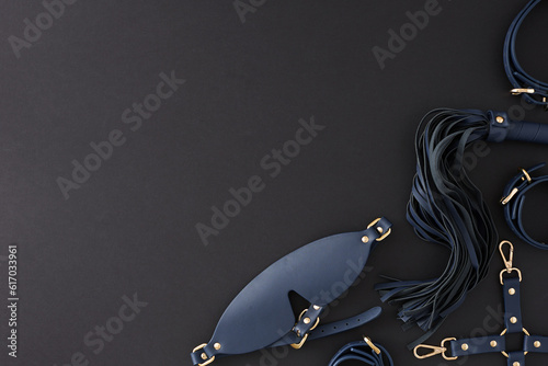 Erotic enjoyment BDSM toy ideas. Top view photo of cuffs, blindfold mask, leather whip on black background with empty space for advert or text
