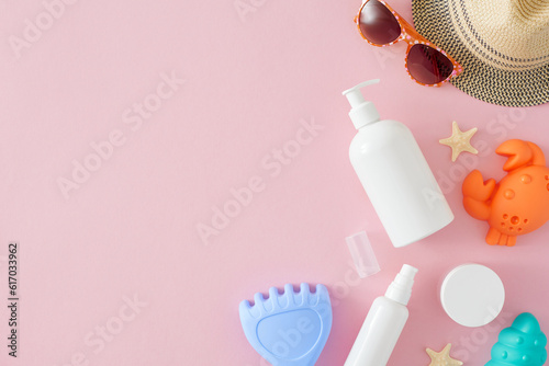 Idea for sun protection skincare for kids. Top view composition of cosmetic bottles, sandbox toys, kids summer accessories, starfish on pastel pink background with space for advert or message