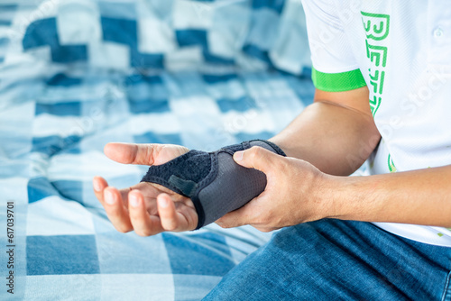 Close up Man holding wrist with soft splint due to wrist injury at home, medical treatment, first aid, Healthcare and medical concept. photo