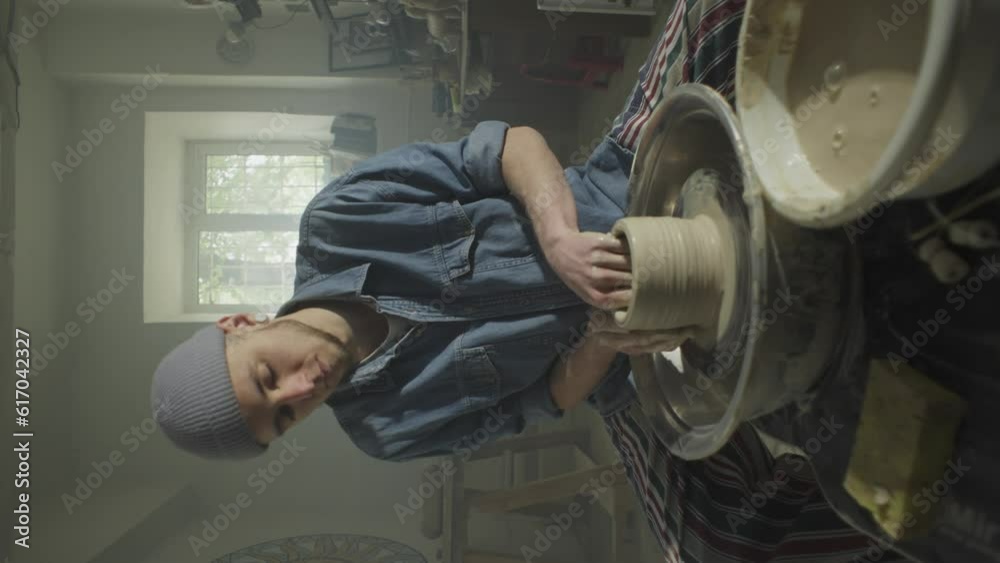 Vertical video of a male potter working with clay in a workshop on a potter's wheel. A beautiful workshop and the work of a ceramist on his own. High quality 4k footage Vertical video of a male potter working with clay in a workshop on a potter's wheel. A beautiful workshop and the work of a ceramist on his own. High quality 4k footage