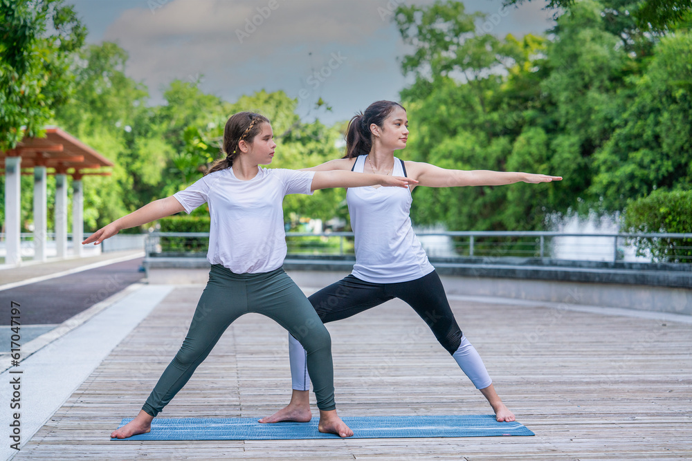 Young indian woman yoga teacher teaches girl practicing stretching poses as morning garden exercise .Healthy concept