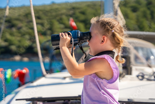 Little girl on a yacht looking through binoculars in the sea © dtatiana