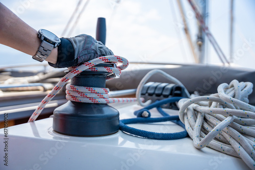 Mans hand pulling winch rope on sailing boat