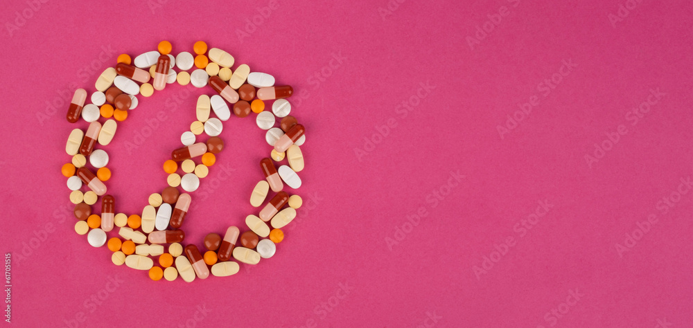 Forbidden sign shaped colorful pills, top view image of forbidden sign shaped colorful pills. No to antibiotic addiction concept image, isolated pink background with copy space. Banner design idea. 
