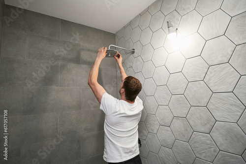 Фотография Male worker fixing bathroom showerhead while working on bathroom renovation