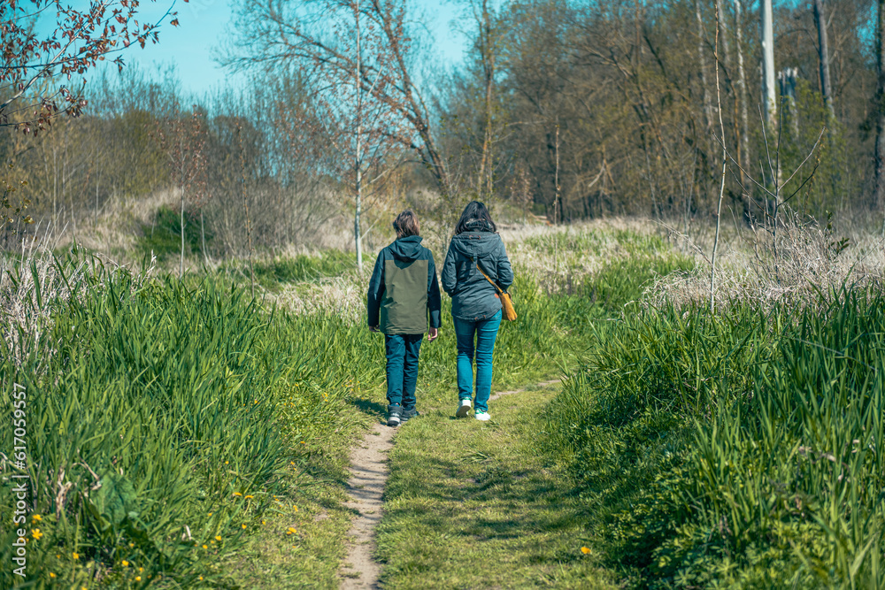 Naklejka premium back view of two persons walking in the woods