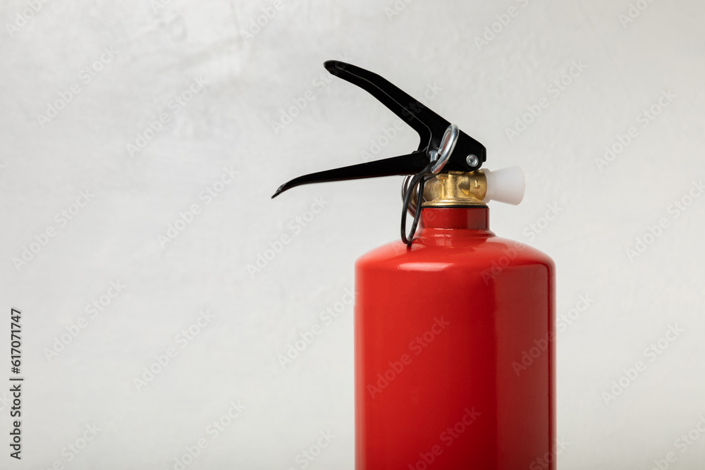 Obraz premium Fire extinguisher on a light texture background. Fire protection, home fire extinguisher. home security concept. Place for text. Copy space.banner