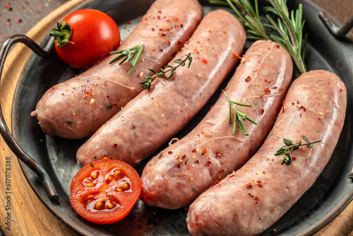 Raw sausages with herbs and spices on a light background. Food recipe background. Close up