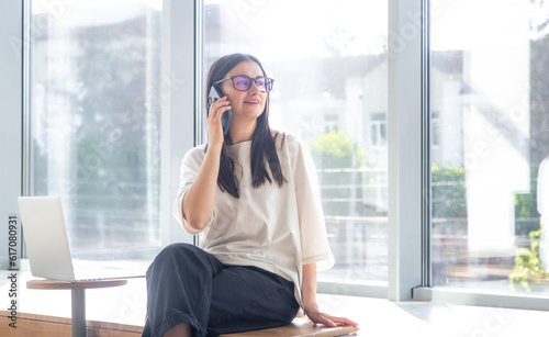 Cheerful young woman in glasses talking on a smartphone in the office. Free Download Cheerful young woman in glasses talking on a smartphone in the office. - GFXLoad