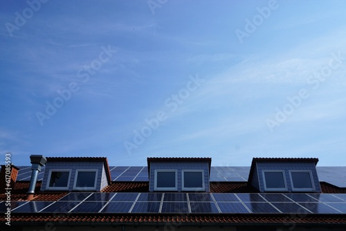 Neus Dach mit Fensterluken, rotem Ziegeln und blauen Solarpanels vor Himmel bei Sonne am Morgen im Sommer