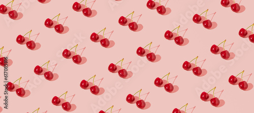 Fresh juicy cherries, creative fruit pattern, dusty rose pink background. 