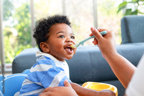 Happy smiling boy with mom while eating in the living room at home. Preschool child development, food menu for 1 year olds
