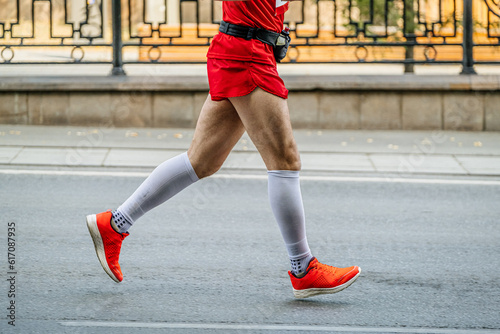 side view male runner run marathon race in white compression socks and bright red running shoes photo