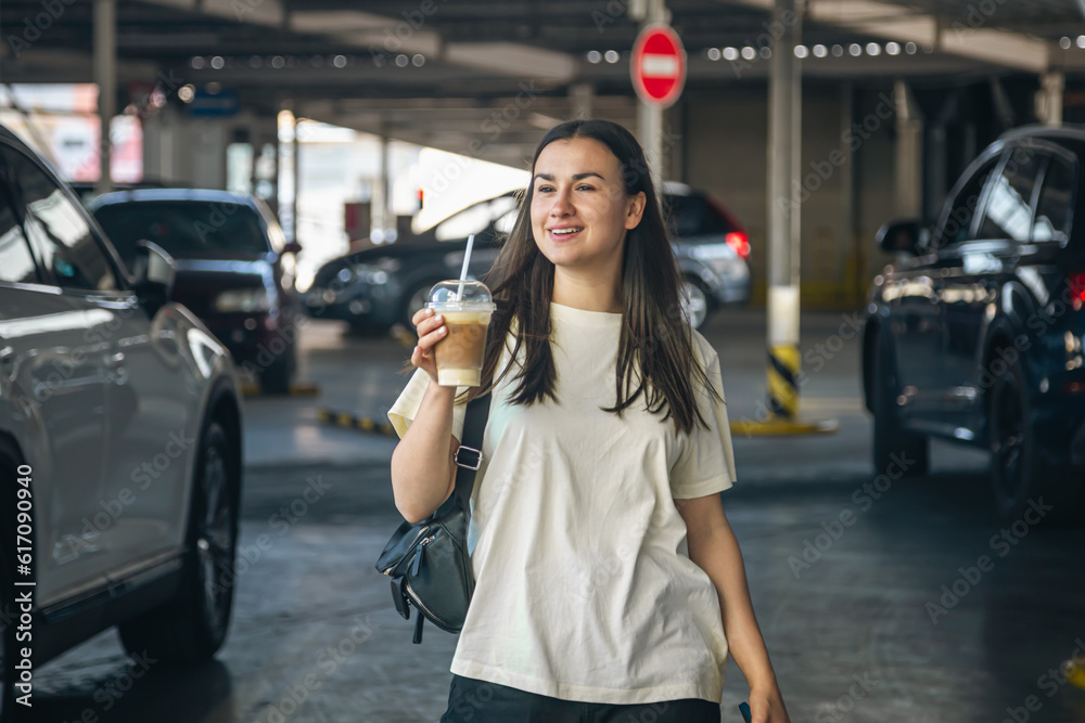 © puhimec - Young woman with a cup of coffee in the parking lot.
