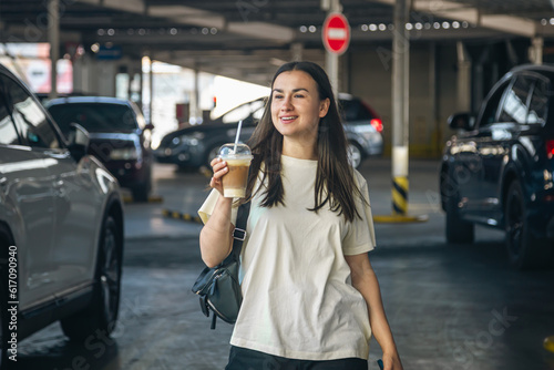 Young woman with a cup of coffee in the parking lot.