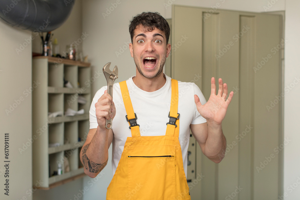 young handsome man feeling happy and astonished at something unbelievable. handyman concept young handsome man feeling happy and astonished at something unbelievable. handyman concept