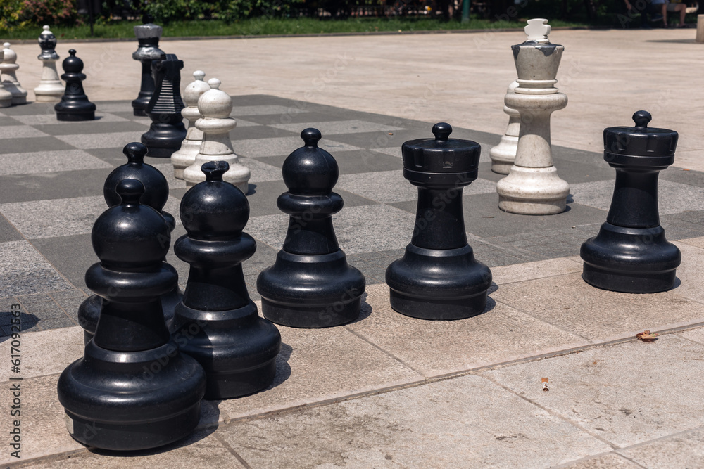 Big plastic chess figures on the stone playground in the park.