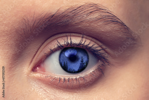 Paranormality, supernatural or mental disorders concepts. Starry night sky over trees in iris. Woman with weird eye, closeup photo