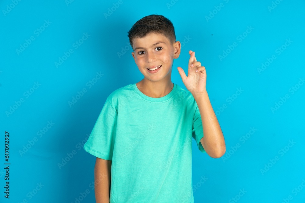 Little hispanic boy wearing green T-shirt pointing up with fingers number ten in Chinese sign language Shi Little hispanic boy wearing green T-shirt pointing up with fingers number ten in Chinese sign language Shi