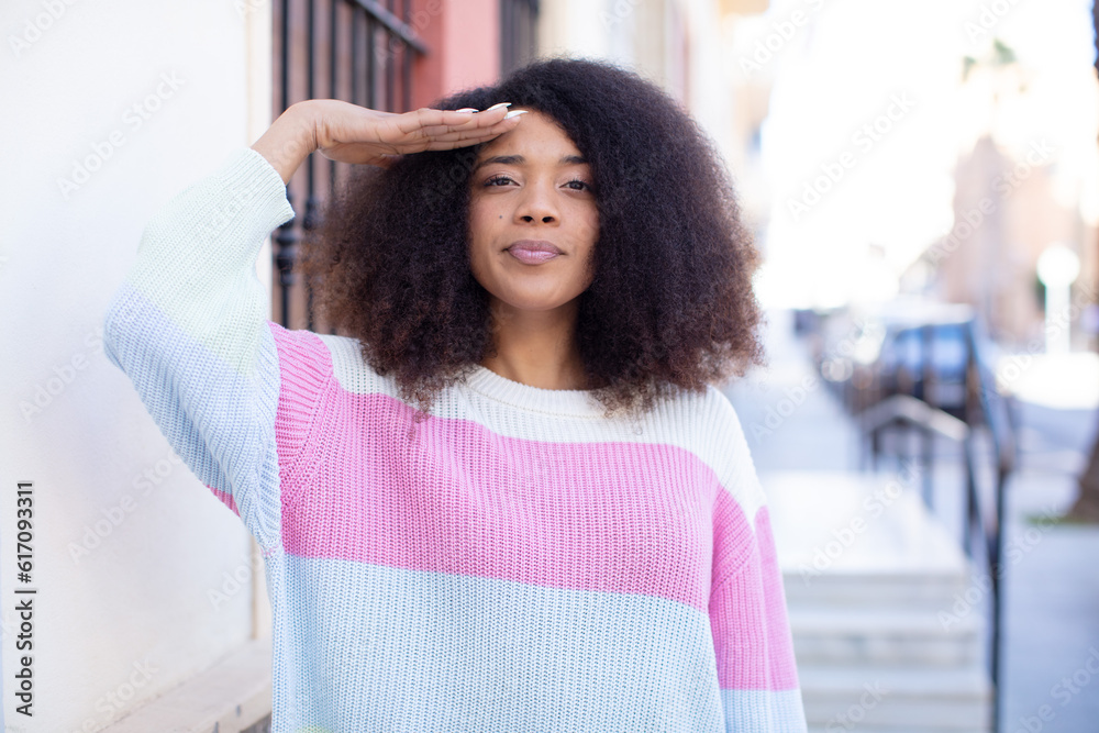 african american pretty woman greeting the camera with a military salute in an act of honor and patriotism, showing respect