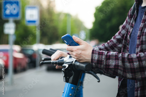 Close up of man hand using mobile app for rental electric scooter.