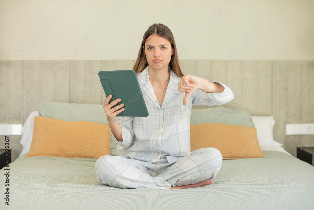 young pretty woman feeling cross,showing thumbs down. touchscreen pad concept