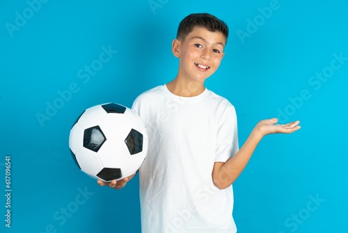 Funny Little hispanic boy wearing white T-shirt holding a soccer ball hold open palm new product great proposition