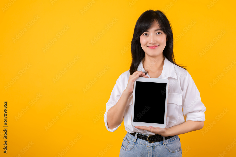 Confident asian woman embraces the digital age, holding tablet on a vibrant yellow background. modern connectivity, tech-savviness, and empowerment. digital lifestyles and technological advancements. Confident asian woman embraces the digital age, holding tablet on a vibrant yellow background. modern connectivity, tech-savviness, and empowerment. digital lifestyles and technological advancements.
