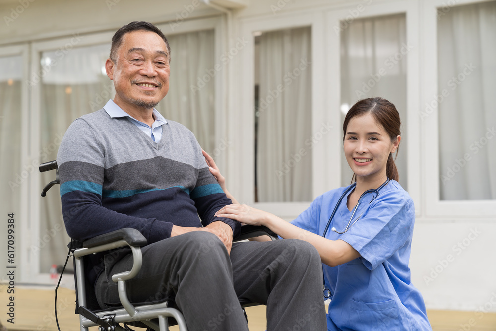Fototapeta premium Nurse and patient senior man on wheelchair. Nurse caring senior man sitting on wheelchair outdoor at hospital. Asian nurse taking care old man in wheelchair in garden at home