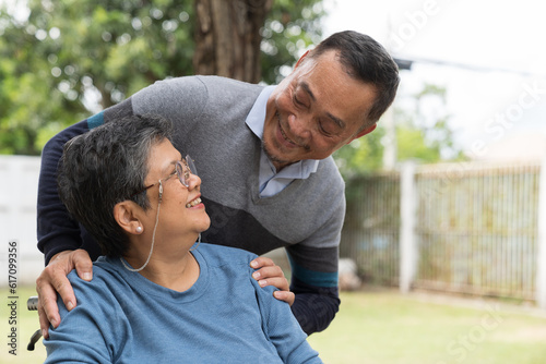 Happy smiling Asian elderly couple hugging together outdoor in garden at home. Retirement, health care, relax and spending time concept