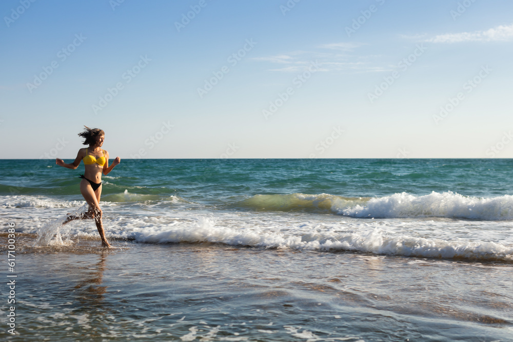 A woman in a bathing suit rests on the sandy seashore and bathes in the waves A woman in a bathing suit rests on the sandy seashore and bathes in the waves