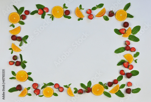 Frame of fresh strawberries   green mint leaves and sliced oranges on white background. Top view  flat lay .Vitamin  fresh  healthy dessert concept. Free copy space. 