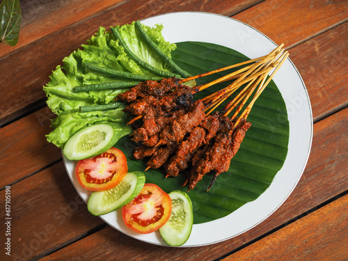 Beef satay from Indonesian Lombok Island called Sate Rembiga. Served with lettuce and tomatoes and cucumbers. photo