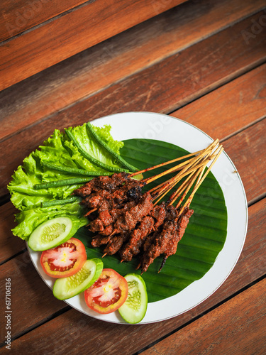 Beef satay from Indonesian Lombok Island called Sate Rembiga. Served with lettuce and tomatoes and cucumbers. photo