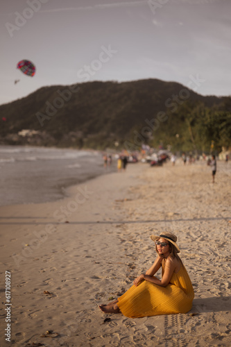 young woman sitting on the beach and watching the sunset