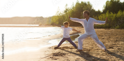 Family  dad and little son practice Tai Chi Chuan in the summer on the beach. solo outdoor activities.  family exercising  together. copy space. banner photo