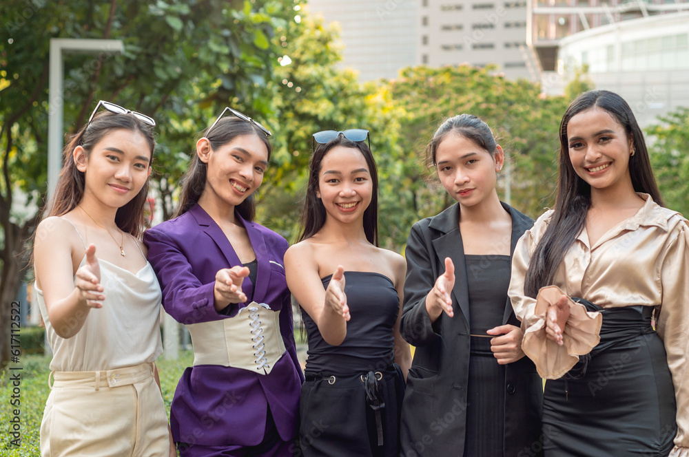 Fototapeta premium 5 friendly and hospitable asian ladies, possibly workmates at the office, offer a handshake. Outdoor scene at the city park.