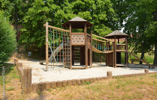 Kids playground construction of wooden huts and climbing net bridge and sand surface ground