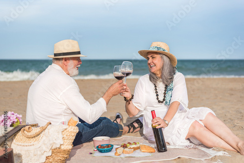Senior couple enjoying picnic on beach photo
