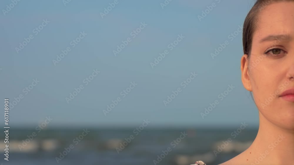 Half portrait of beautiful young woman without makeup on her face at sunset. Close up footage, blinking female eye at sea waves background. Relax leisure activity, active lifestyle, cheerful confident Half portrait of beautiful young woman without makeup on her face at sunset. Close up footage, blinking female eye at sea waves background. Relax leisure activity, active lifestyle, cheerful confident