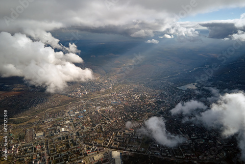 Aerial view from airplane window at high altitude of distant city covered with puffy cumulus clouds forming before rainstorm © bilanol
