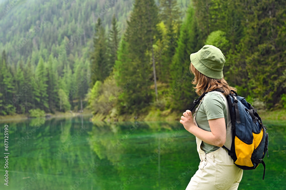 a girl with a backpack is looking at a Green lake Austria