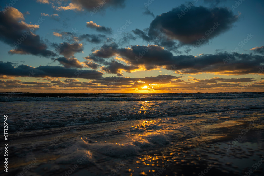 Obraz premium Ocean sunset landscape with soft evening sea water waves crushing on sandy beach