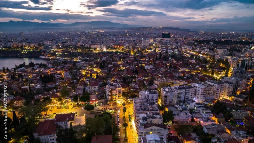 Forwards fly above large city at sunset. aerial hyperlapse shot of illuminated urban neighbourhoods against colourful sky. Antalya, Turkey