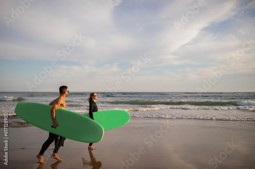 Summer Activities. Happy Young Couple Carrying Surfboards Walking Along Shoreline